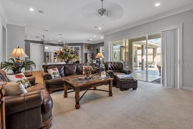 living area featuring recessed lighting, light colored carpet, a ceiling fan, and ornamental molding