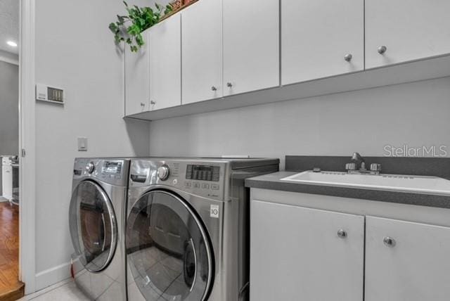 washroom with washer and clothes dryer, cabinet space, baseboards, and a sink