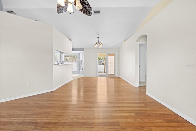 unfurnished living room featuring baseboards, visible vents, arched walkways, ceiling fan, and light wood-style floors