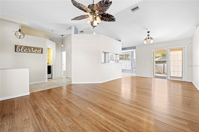 unfurnished living room featuring light wood finished floors, visible vents, ceiling fan with notable chandelier, and baseboards