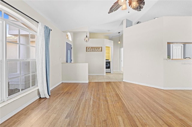 unfurnished living room featuring visible vents, baseboards, washer / dryer, wood finished floors, and a ceiling fan