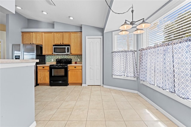 kitchen featuring an inviting chandelier, light tile patterned flooring, stainless steel appliances, vaulted ceiling, and light countertops