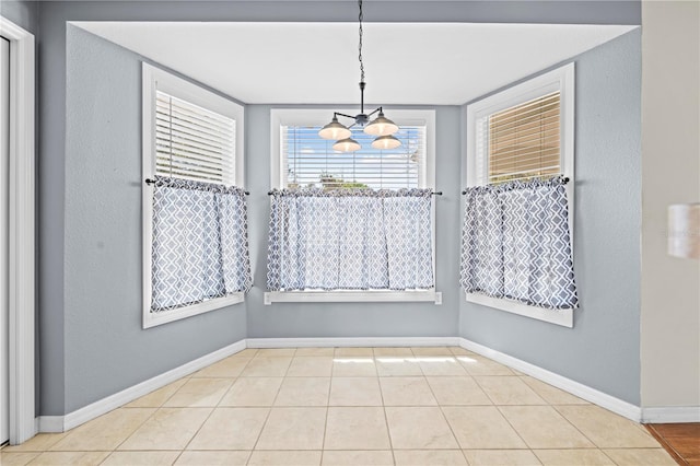 unfurnished dining area with baseboards, a chandelier, and tile patterned flooring