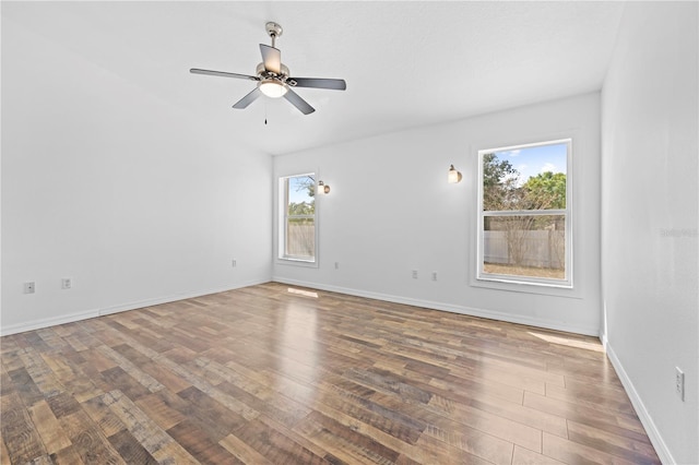 spare room with a wealth of natural light, baseboards, wood finished floors, and a ceiling fan