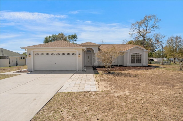 view of front facade featuring concrete driveway, fence, a garage, and stucco siding