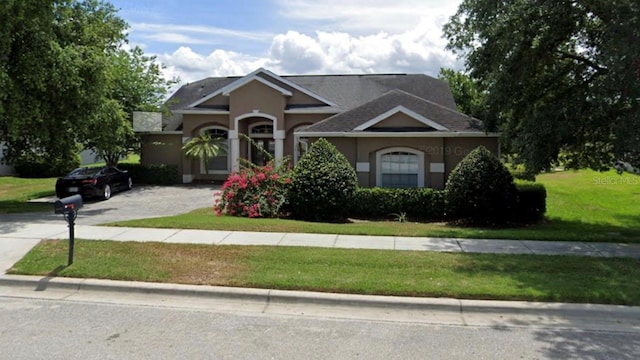 view of front of property with stucco siding, driveway, and a front yard