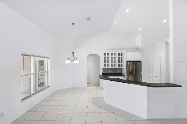 kitchen with dark countertops, glass insert cabinets, stainless steel refrigerator with ice dispenser, arched walkways, and white cabinetry