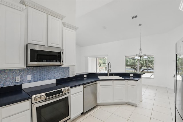 kitchen featuring dark countertops, a peninsula, stainless steel appliances, and a sink