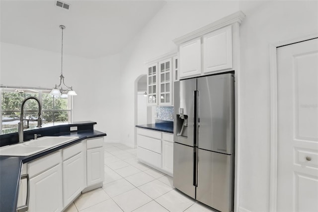 kitchen featuring visible vents, arched walkways, a sink, dark countertops, and stainless steel fridge