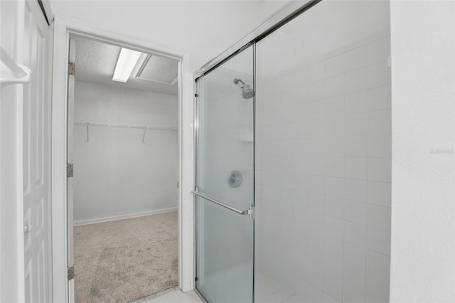 bathroom with a spacious closet, a stall shower, and a textured ceiling