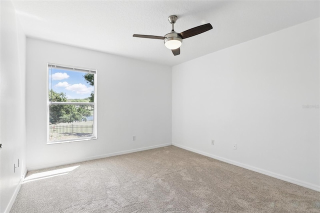 carpeted empty room with baseboards and a ceiling fan