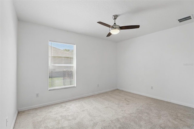 carpeted empty room with visible vents, baseboards, and ceiling fan