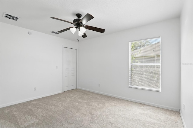 empty room featuring a ceiling fan, carpet, visible vents, and baseboards