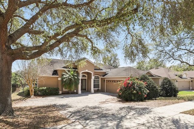 view of front of home featuring a garage, stucco siding, driveway, and fence