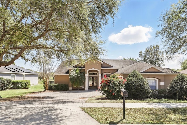 ranch-style home featuring stucco siding, a front lawn, and driveway