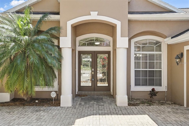 view of exterior entry with stucco siding and french doors