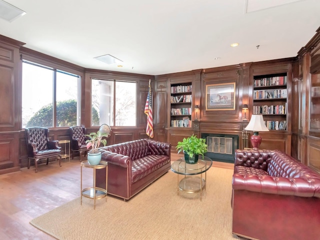 living room featuring a glass covered fireplace, built in shelves, and wood finished floors