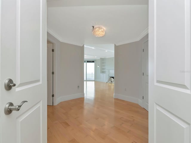 corridor featuring baseboards, light wood-style floors, and ornamental molding