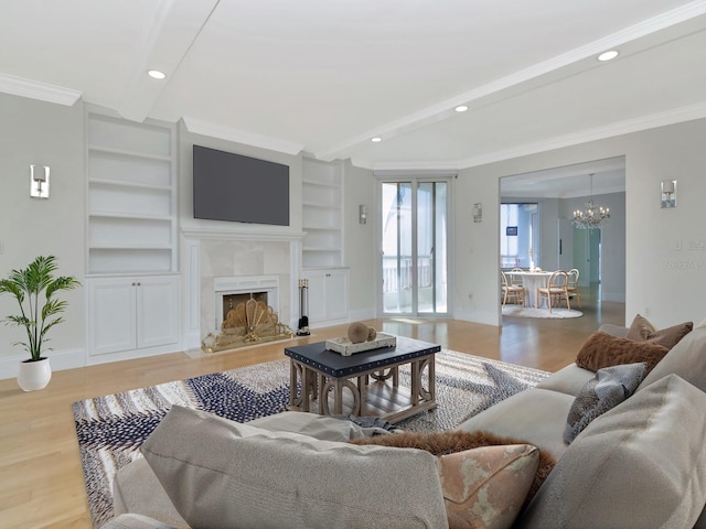 living area with an inviting chandelier, wood finished floors, baseboards, and ornamental molding