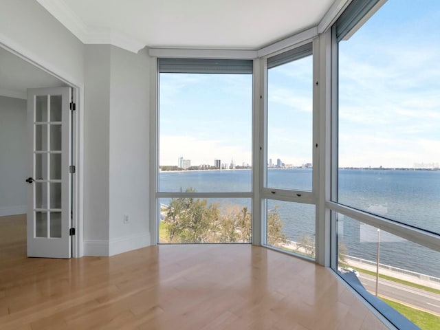 interior space featuring crown molding, wood finished floors, a water view, and expansive windows