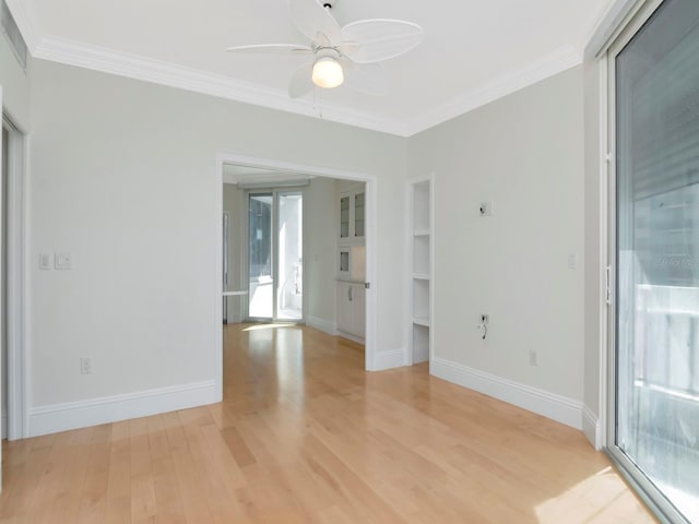 spare room with crown molding, light wood-style floors, baseboards, and ceiling fan