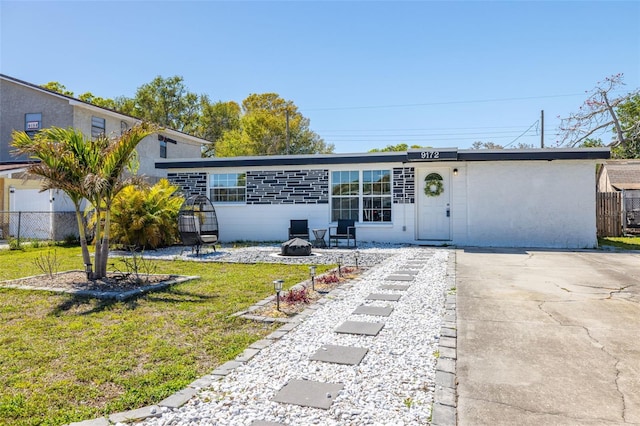 view of front of house with a fire pit, a front yard, and fence