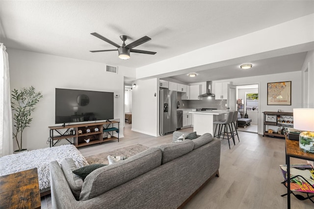 living area featuring visible vents, light wood finished floors, and ceiling fan