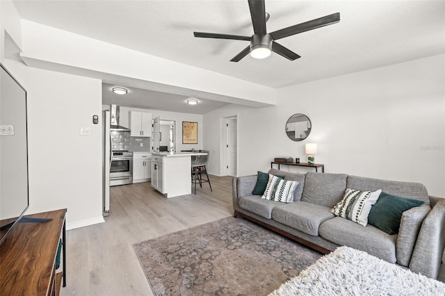 living room featuring light wood finished floors, baseboards, and ceiling fan