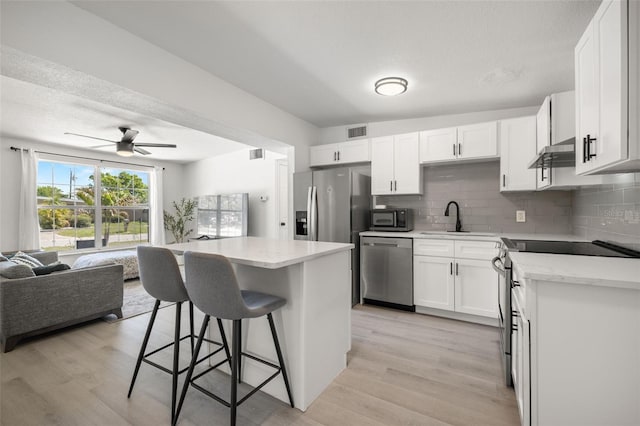 kitchen featuring visible vents, open floor plan, a breakfast bar area, appliances with stainless steel finishes, and a sink