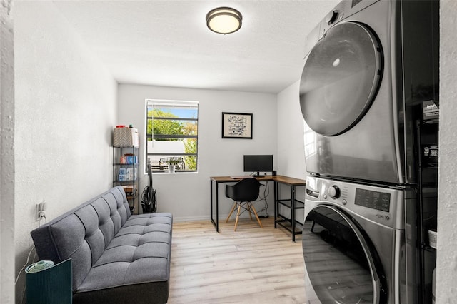 washroom with baseboards, laundry area, stacked washer and clothes dryer, wood finished floors, and a textured ceiling