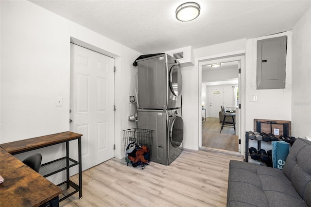 clothes washing area featuring light wood-type flooring, visible vents, stacked washer and clothes dryer, electric panel, and laundry area