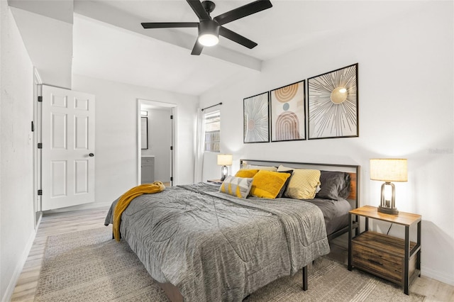 bedroom featuring wood finished floors, baseboards, vaulted ceiling with beams, ceiling fan, and connected bathroom