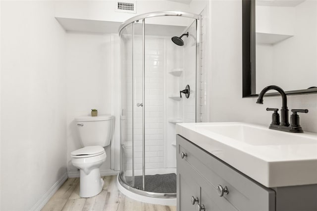 bathroom featuring a shower stall, toilet, wood finished floors, and visible vents