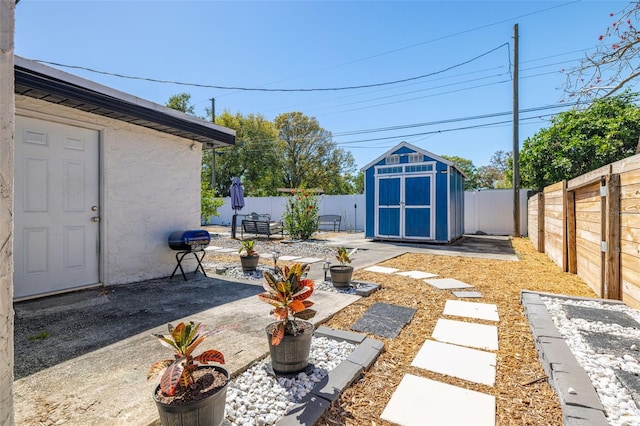 view of yard with a patio, an outbuilding, a fenced backyard, and a shed