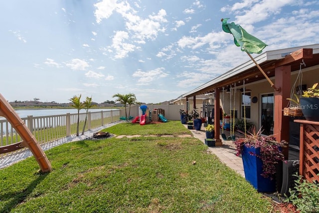 view of yard with a patio area, a playground, a fenced backyard, and a water view