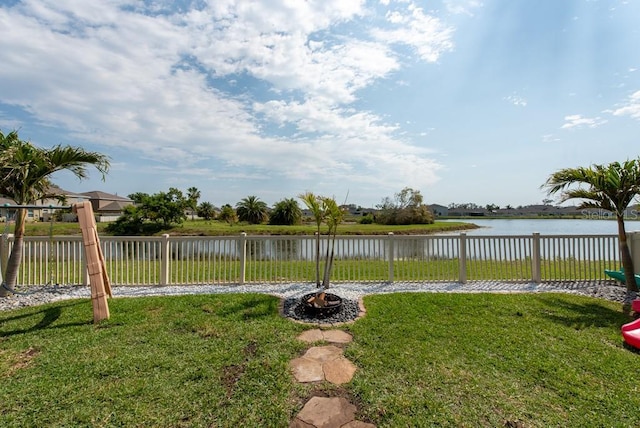 view of yard featuring an outdoor fire pit, a fenced backyard, and a water view