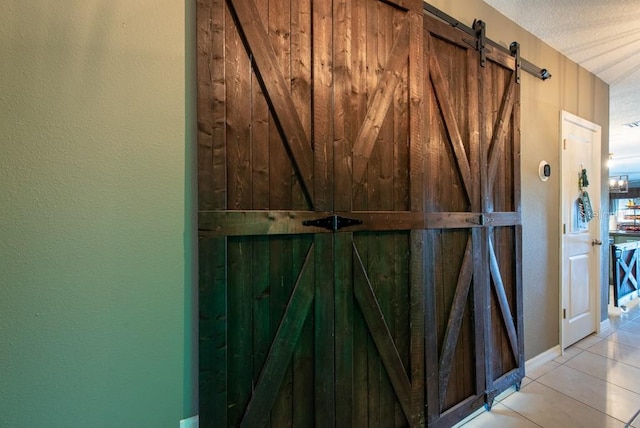 room details with a barn door, a textured wall, and a textured ceiling