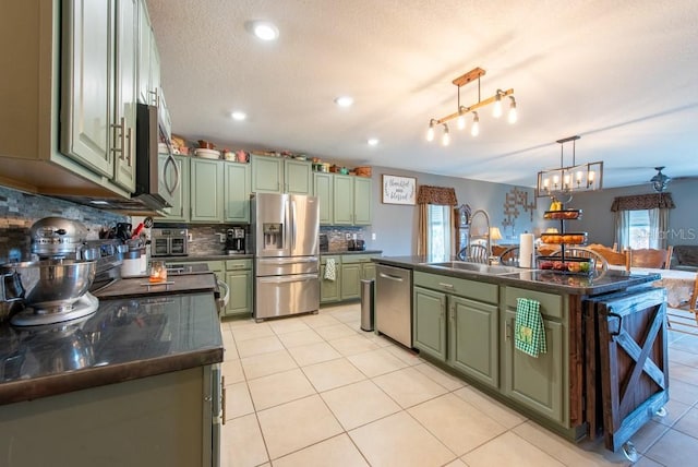 kitchen featuring green cabinetry, stainless steel appliances, dark countertops, and a wealth of natural light