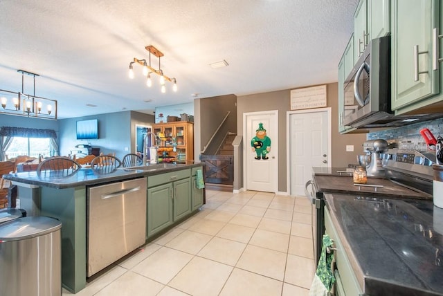 kitchen with light tile patterned floors, green cabinetry, stainless steel appliances, a textured ceiling, and dark countertops