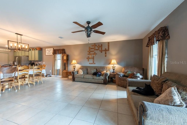 living area featuring light tile patterned floors, visible vents, and ceiling fan with notable chandelier