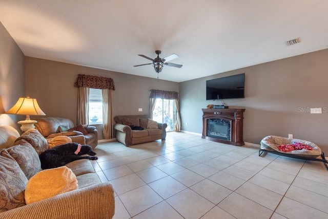 living room featuring visible vents, ceiling fan, baseboards, light tile patterned floors, and a fireplace