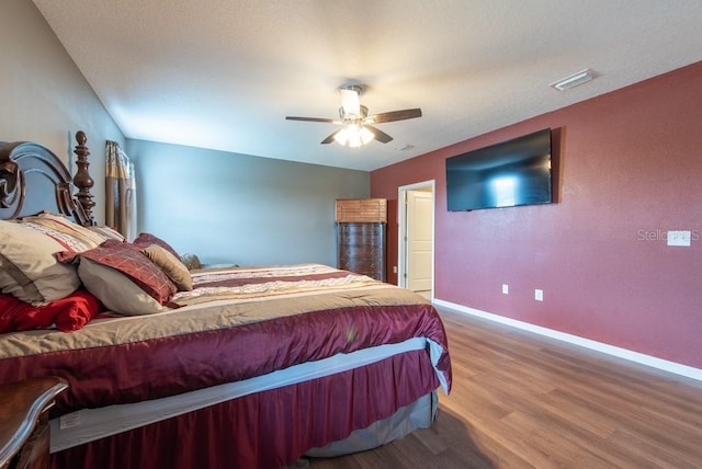 bedroom with ceiling fan, visible vents, baseboards, and wood finished floors