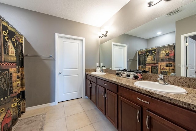 bathroom featuring tile patterned flooring, double vanity, visible vents, and a sink