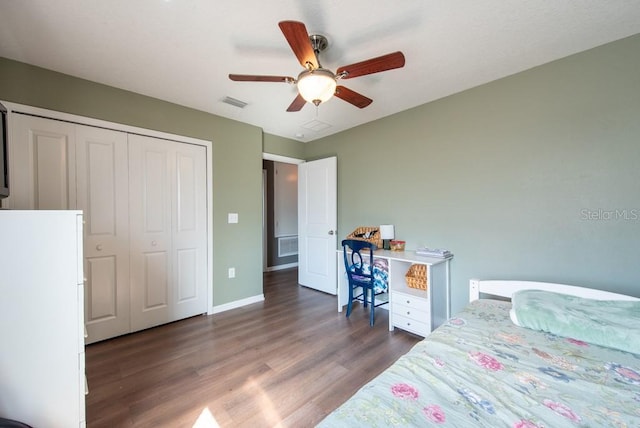 bedroom featuring visible vents, wood finished floors, freestanding refrigerator, a closet, and baseboards