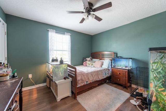 bedroom featuring ceiling fan, a textured ceiling, baseboards, and wood finished floors