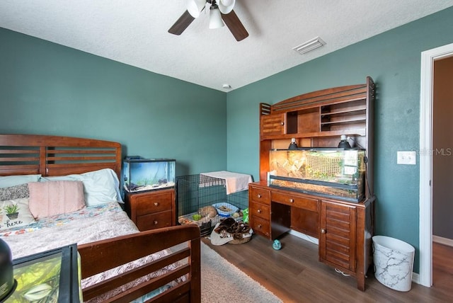 bedroom with ceiling fan, visible vents, a textured ceiling, and wood finished floors