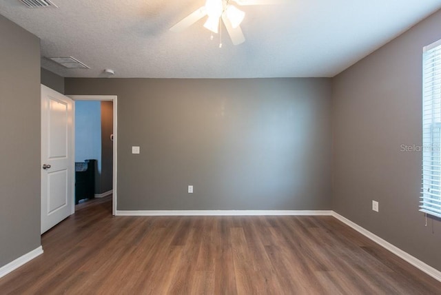 empty room featuring wood finished floors, baseboards, and a wealth of natural light