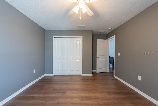 unfurnished bedroom featuring visible vents, baseboards, dark wood-style flooring, and a closet