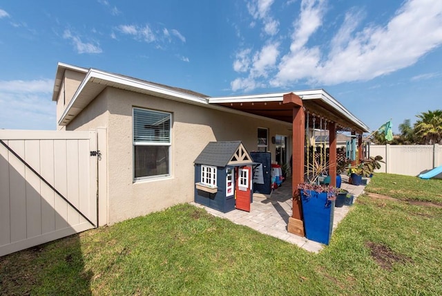 rear view of property featuring stucco siding, a patio, a lawn, and a fenced backyard