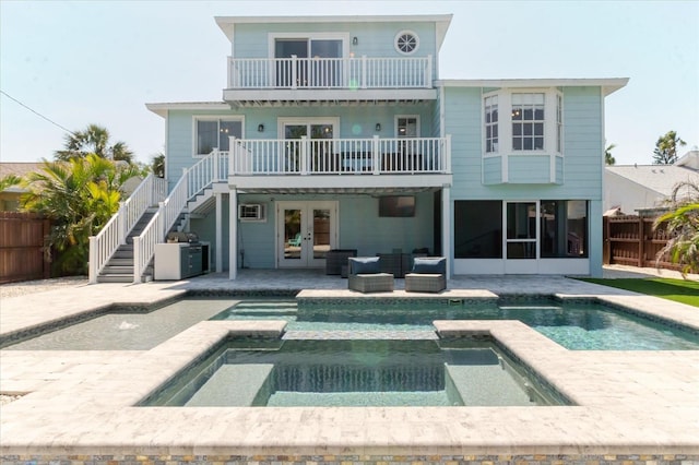 rear view of house featuring fence, stairs, french doors, a balcony, and a patio